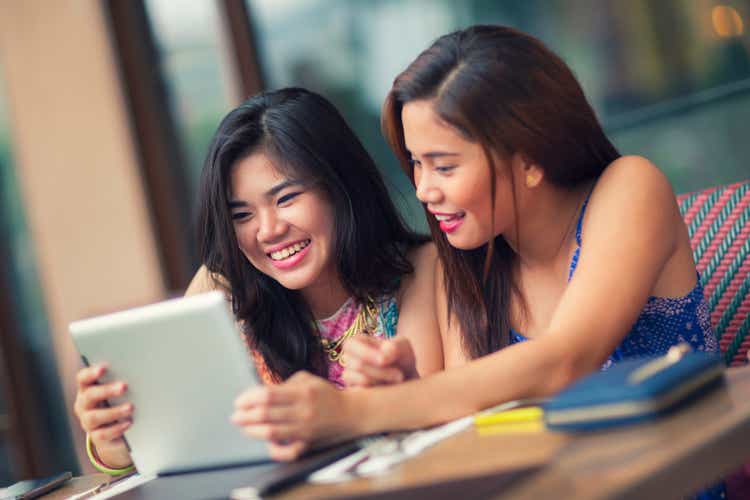 Two young women at a table using a tablet computer