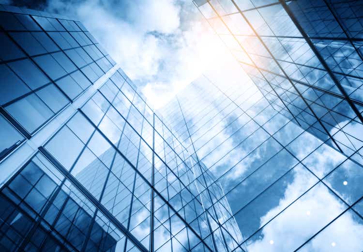 view of a contemporary glass skyscraper reflecting the blue sky