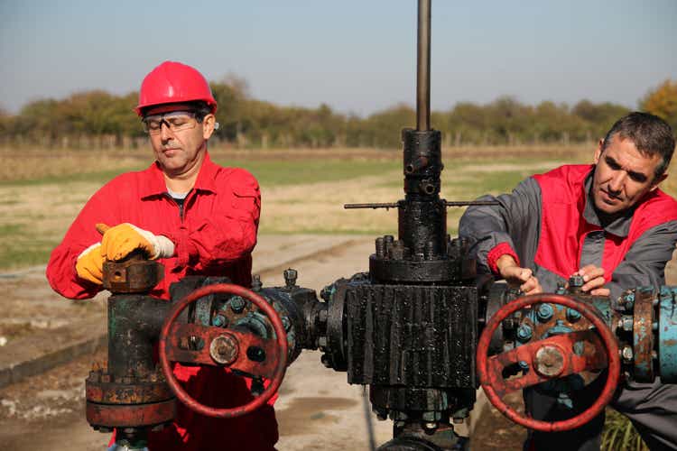 Two Skilled Oil and Gas Engineers in Action at Oil Well