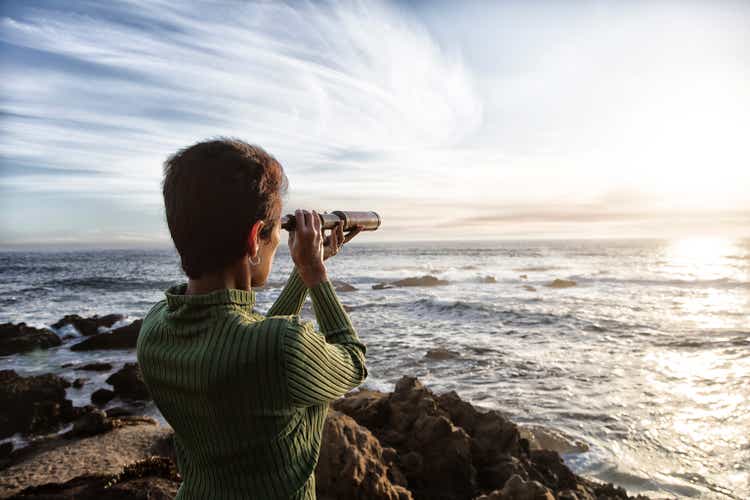 Woman with spyglass looking toward ocean