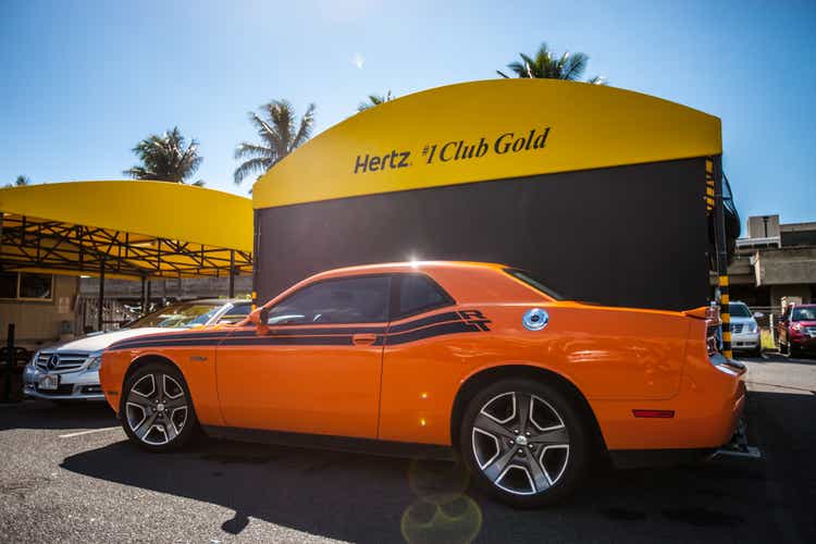Orange Dodge Challenger parked near Hertz rental office