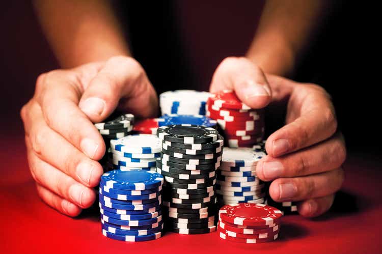 Man"s hands move the winnings casino chips on red table.