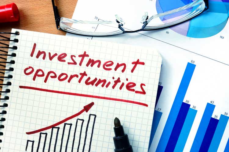 Notepad with investment opportunities on office wooden table.