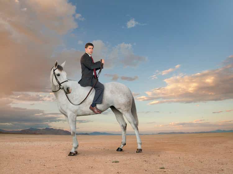 Middle Eastern businessman riding horse backwards