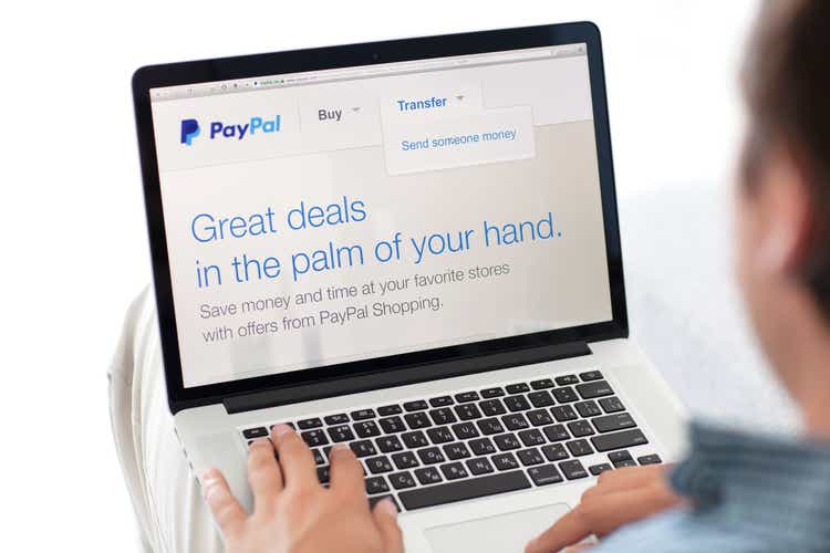 man sitting the MacBook retina with site PayPal on screen