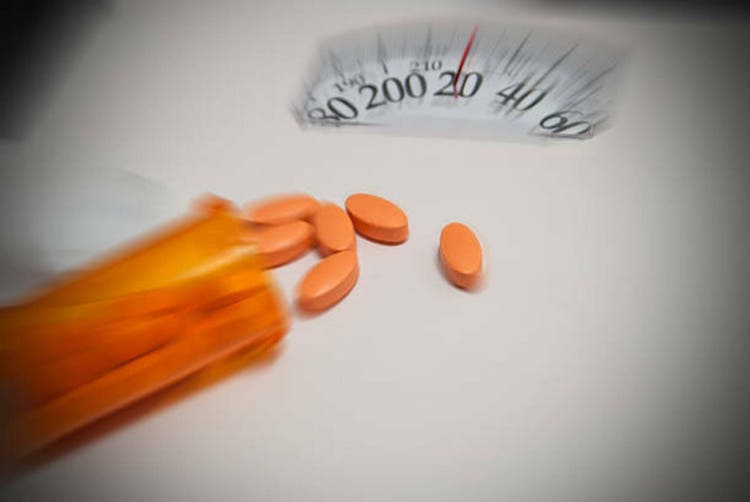 Diet pills on bathroom scales with bokeh effect and zoom