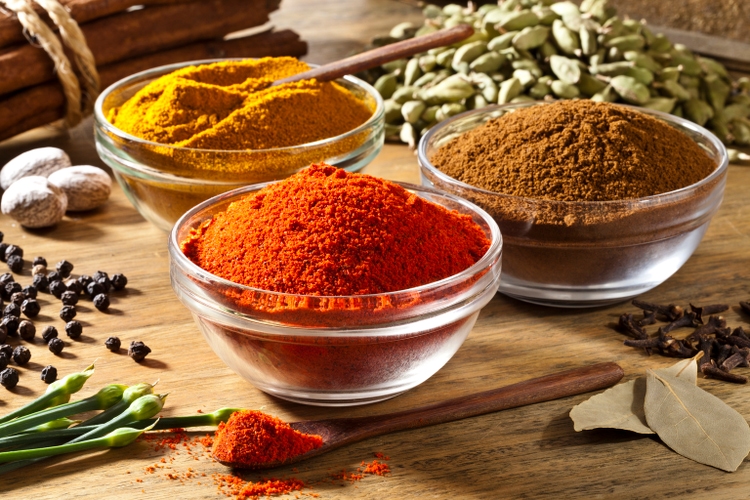 Three bowls filled with spices on rustic wood table