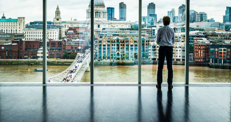 Businessman looks at the London Skyline from his Office Window