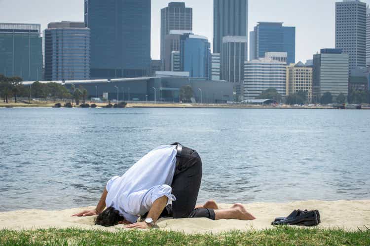 Hispanic businessman burying his head in sand on beach, Perth, Western Australia, Australia