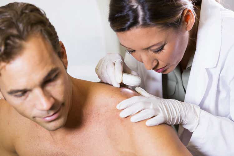 Dermatologist examining patient"s skin for signs of cancer