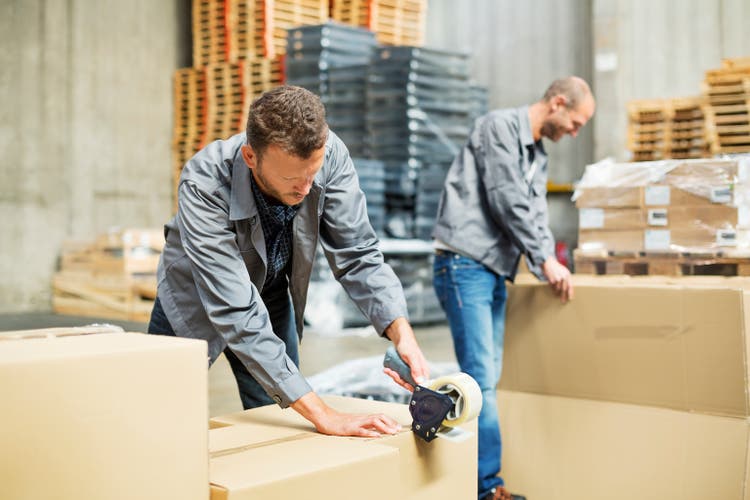Worker packing cardboard boxes in warehouse