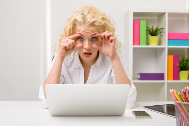 Woman working on computer and holding her eyes open