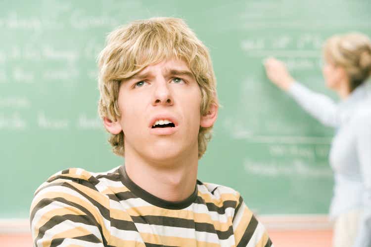 High-school boy looking confused in classroom