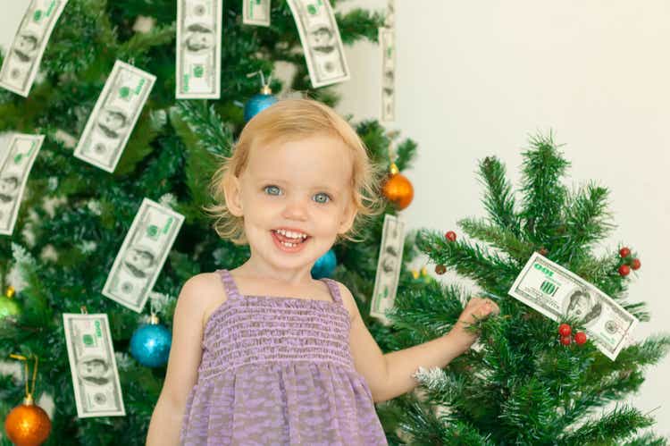 Little girl posing near the christmas tree decorated with dollar