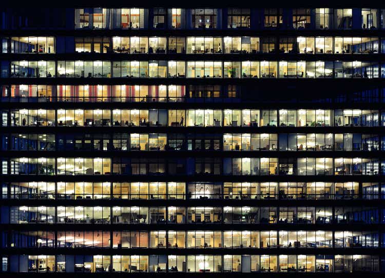 Workers working late. Office windows by night.
