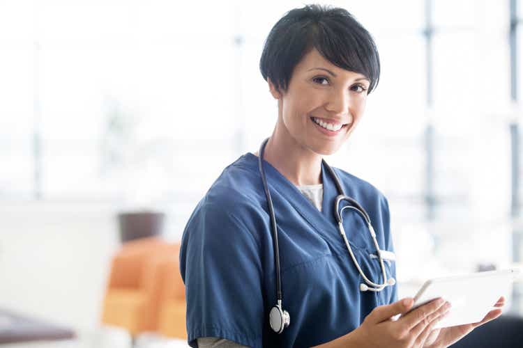 Portrait of female doctor with stethoscope around neck, holding digital tablet