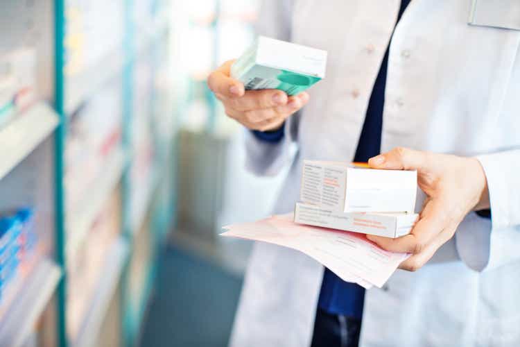 Pharmacist"s hands taking medicines from shelf