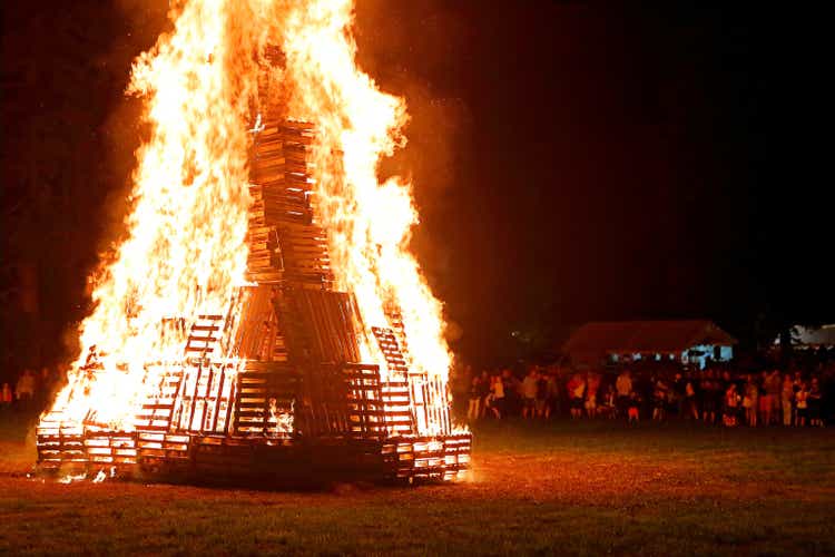 Crowd of people meeting around big bonfire in summer