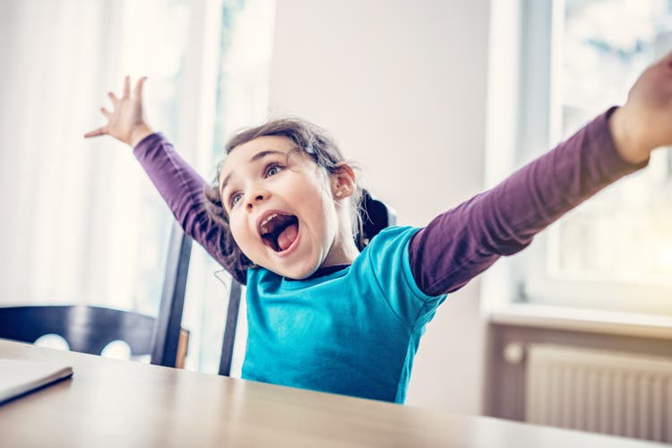 happy cute little girl cheering at desk