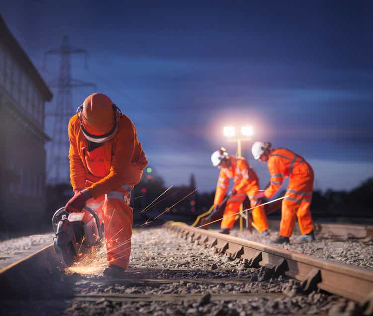 Railway maintenance workers using grinder on track at night