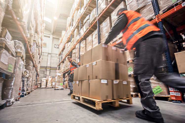 Motion blur of two men moving boxes in a warehouse