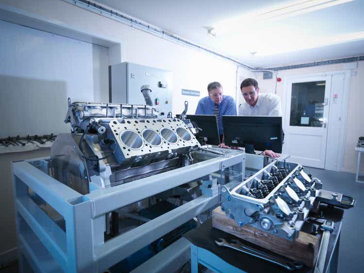 Engineers inspecting automotive engine in test facility