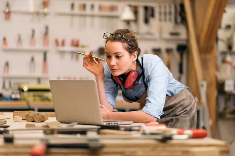 young carpenter in wood workshop using labtop