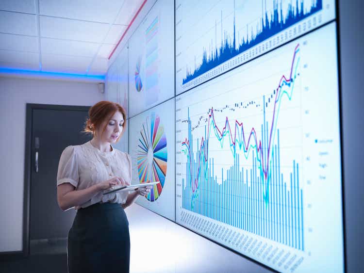 Businesswoman studying graphs on screen with digital tablet