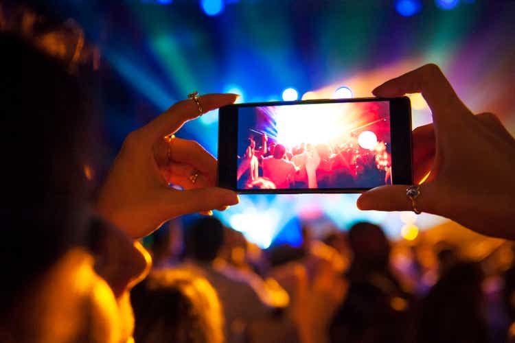 Woman taking a photo with phone at music event