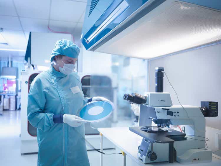 Electronics worker in clean room with silicon wafer