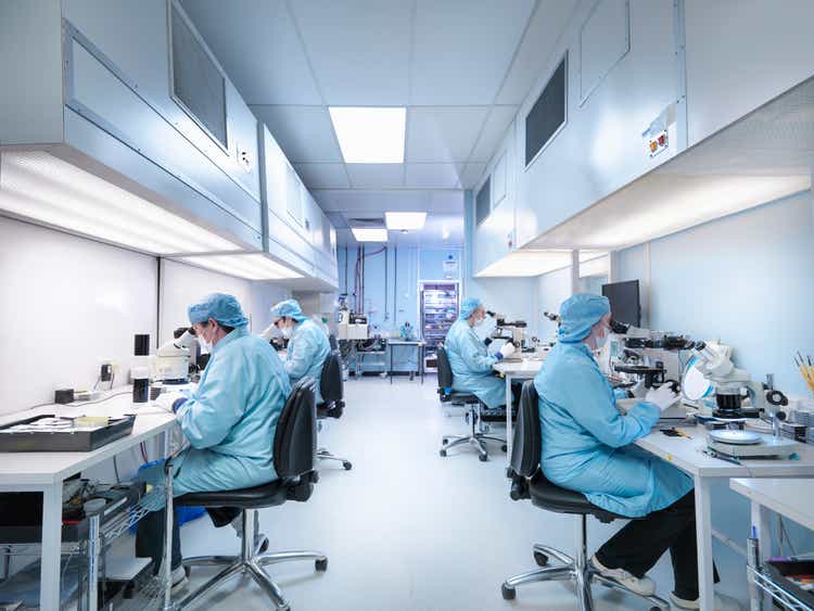 Electronics workers in clean room assembling electronic components