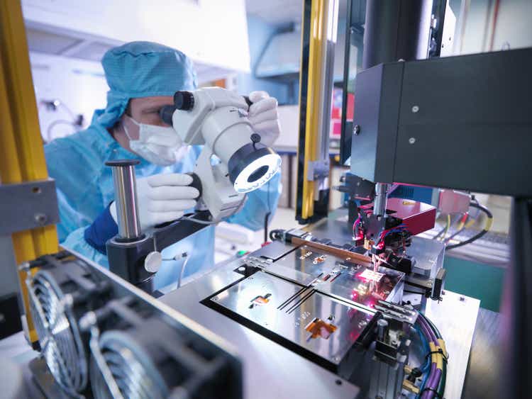 Electronics worker checking a component in a clean room