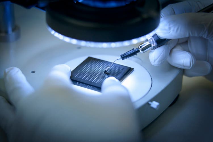 Electronics worker checking small electronic chips in clean room lab, close up