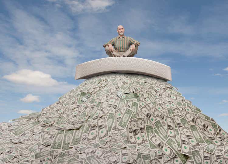 Caucasian businessman sitting on mattress on mountain of money