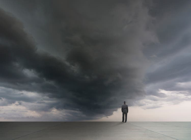 Mixed race businessman standing under stormy sky