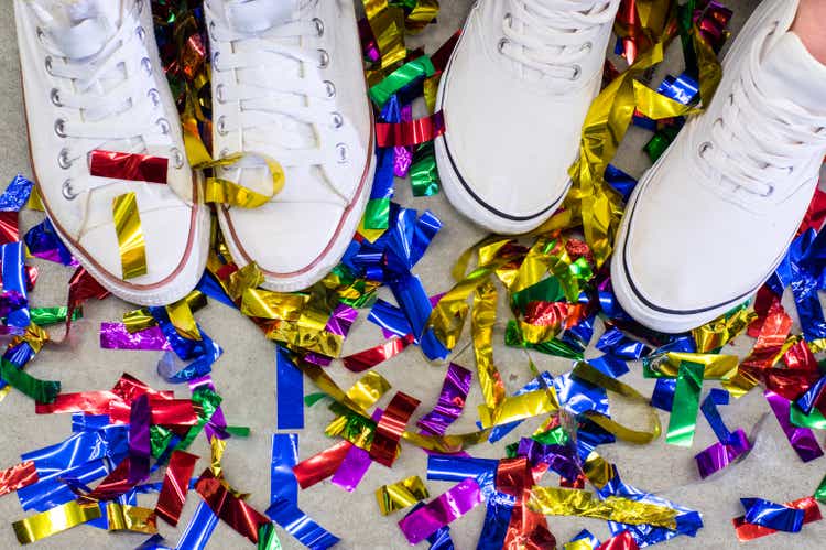 Two feet in white shoes between multicolored festive confetti