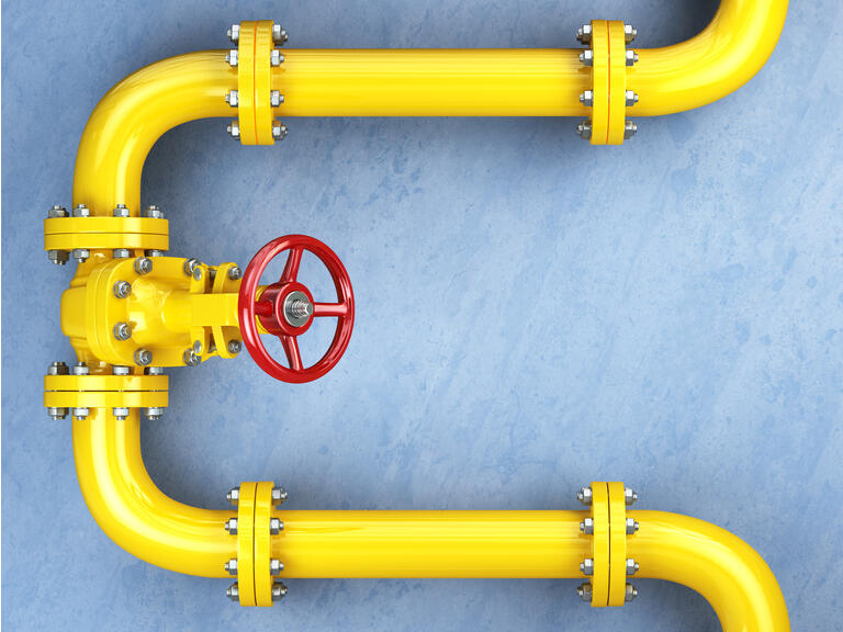 Yellow gas pipeline valve on a blue wall.
