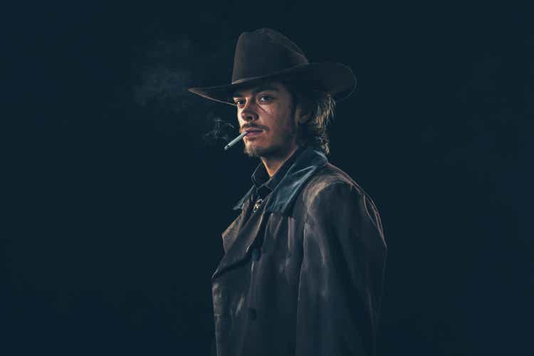 Retro cowboy smoking cigarette. Young man. Studio shot.