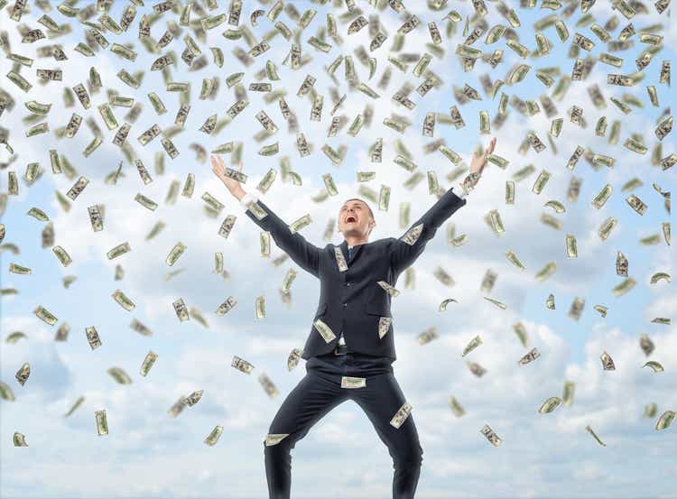 Happy businessman in celebrating pose with loads of money in