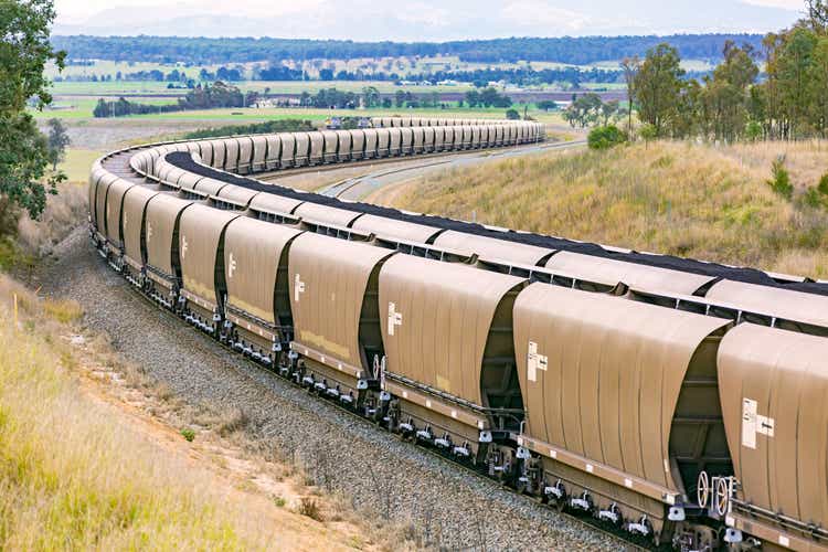 Empty coal train curving past loaded freight cars on grade