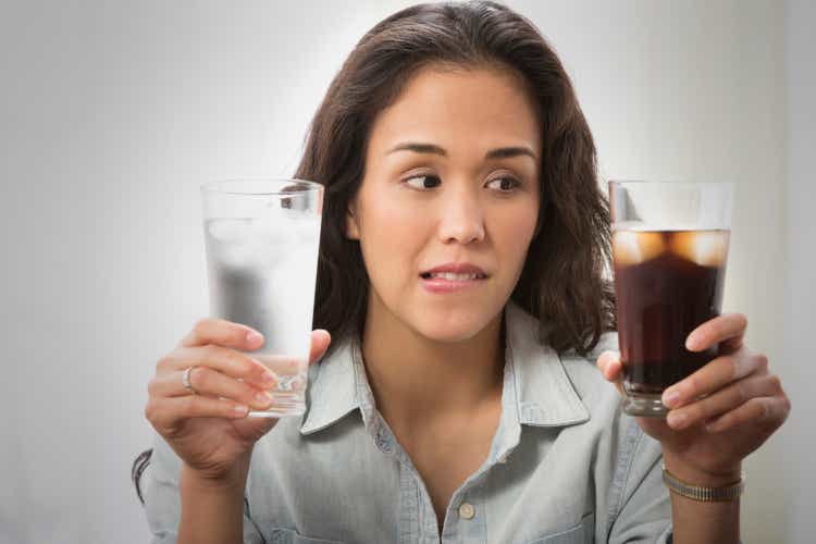 Mixed race woman choosing between soda and water