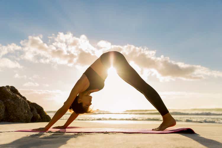 Athlete in downward facing dog position on shore