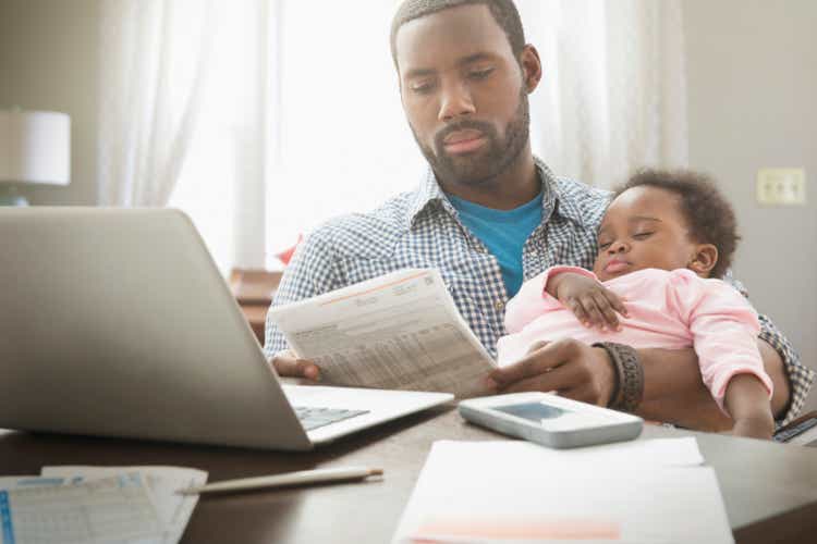 Father holding baby daughter and working from home