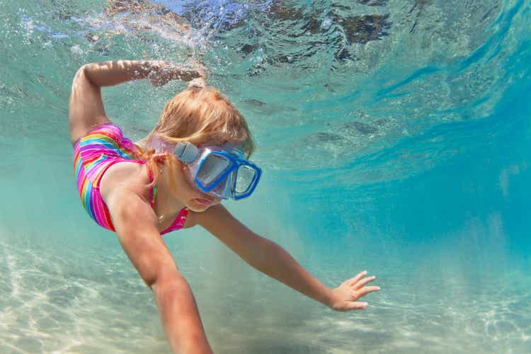 Happy baby girl dive underwater in sea pool