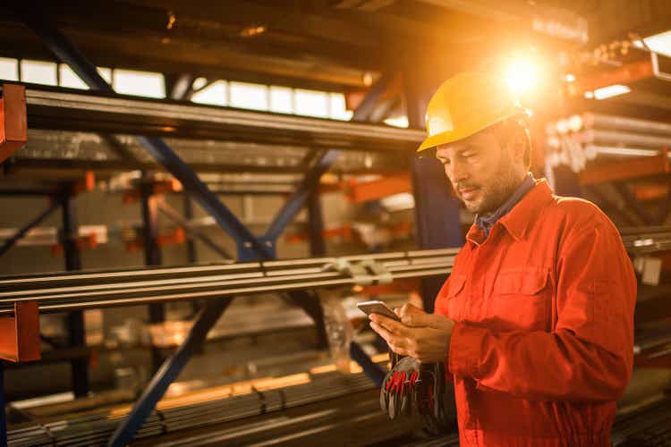 Manual worker text messaging on cell phone in aluminum mill.