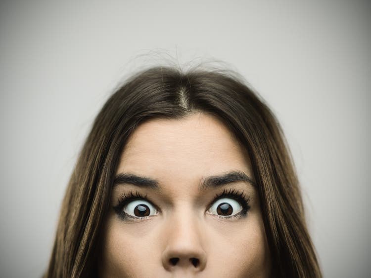 Surprised woman smiling against gray background