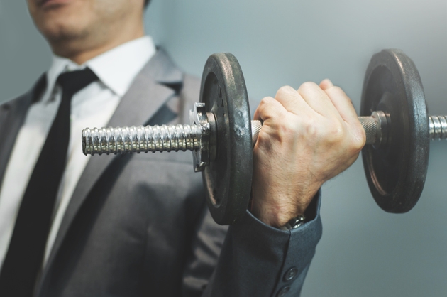 Wellness, healthy concepts. Businessman lifting dumbbell at office.