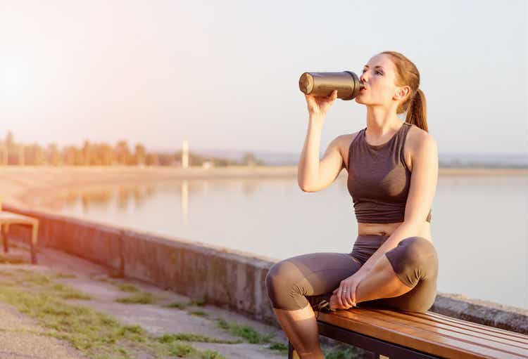 young girl drinks a protein cocktail from a schweeter after jogging