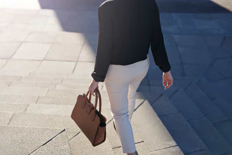 Businesswoman walking on staircase with bag