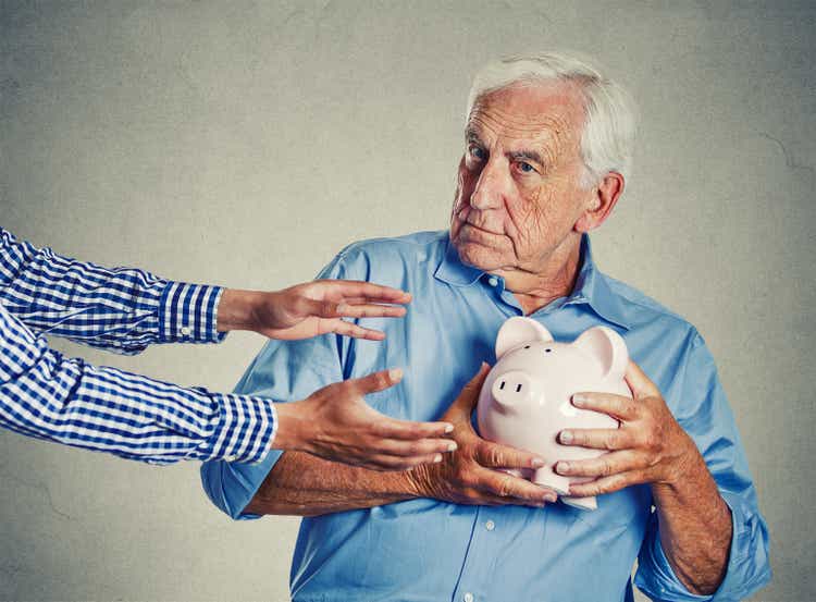 Senior man grootvader holding piggy bank op zoek verdachte proberen te beschermen zijn spaargeld tegen wordt gestolen
